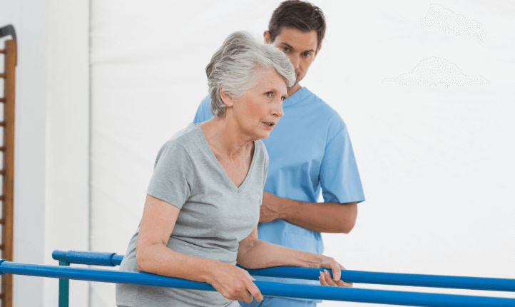 Older woman struggling to walk between parallel bars